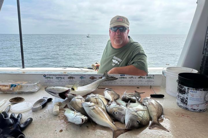 a man holding a fish on a boat in the water