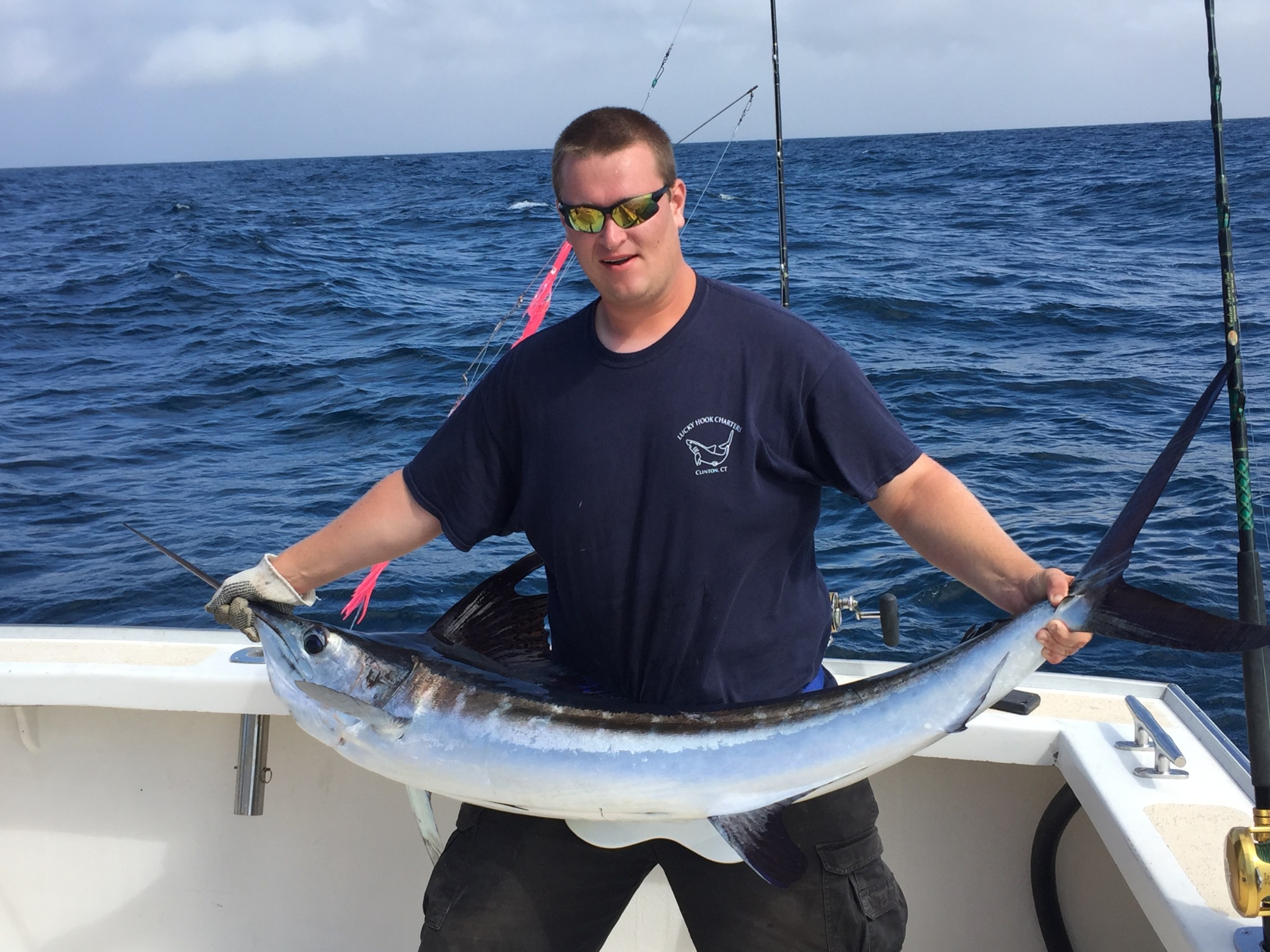 a man holding a fish on a boat in a body of water
