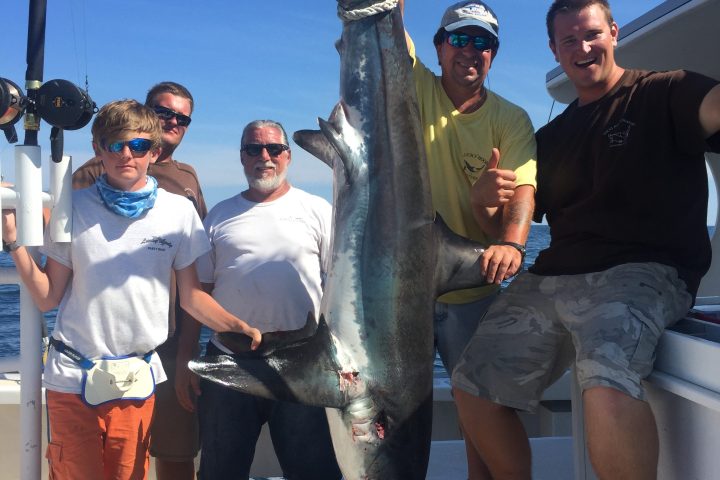 a group of people standing next to a man holding a fish