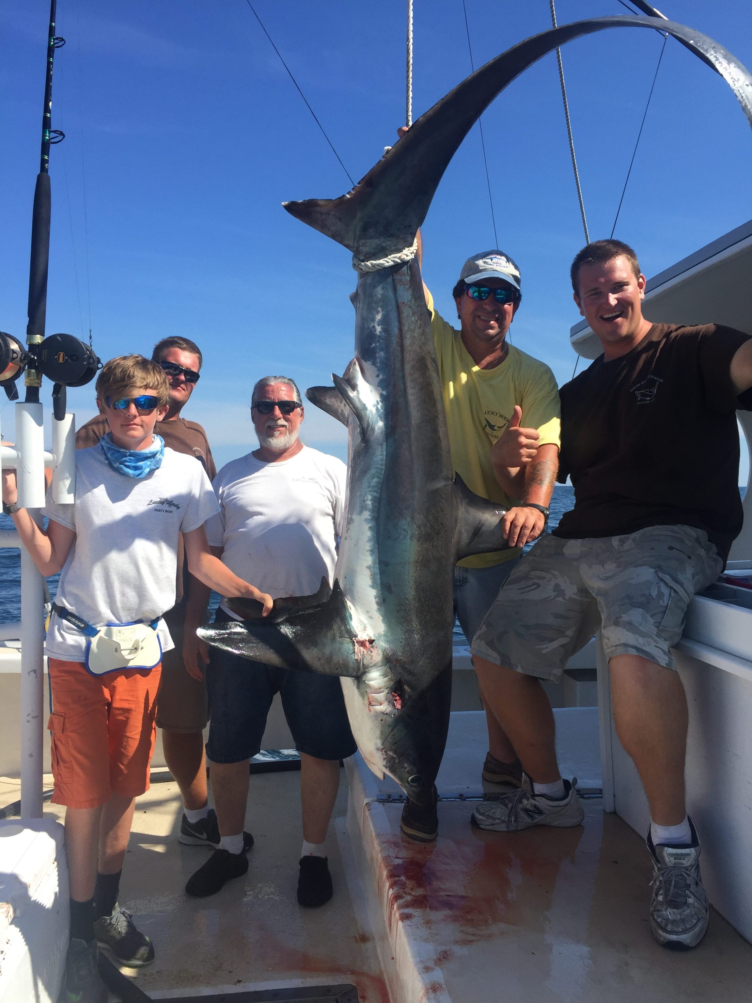 a group of people standing next to a man holding a fish
